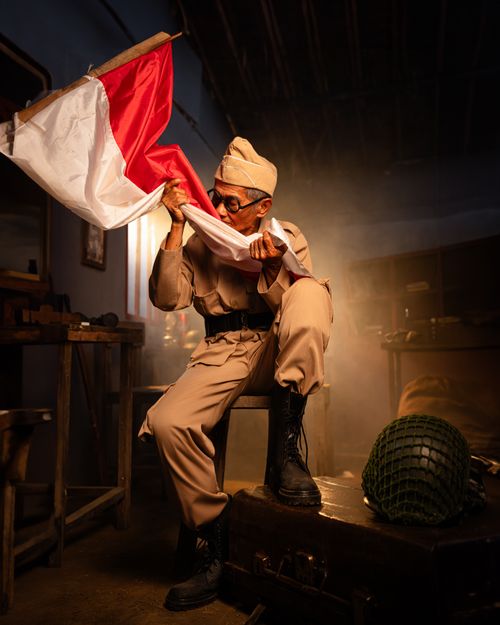 Free Elderly veteran with the Indonesian flag indoors, highlighting national pride and history. Stock Photo