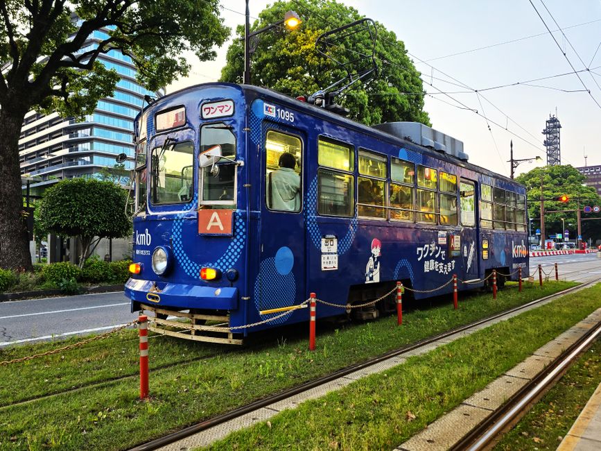Colorful tram captured at dusk on a city street in Kumamoto, Japan, highlighting urban transportation.