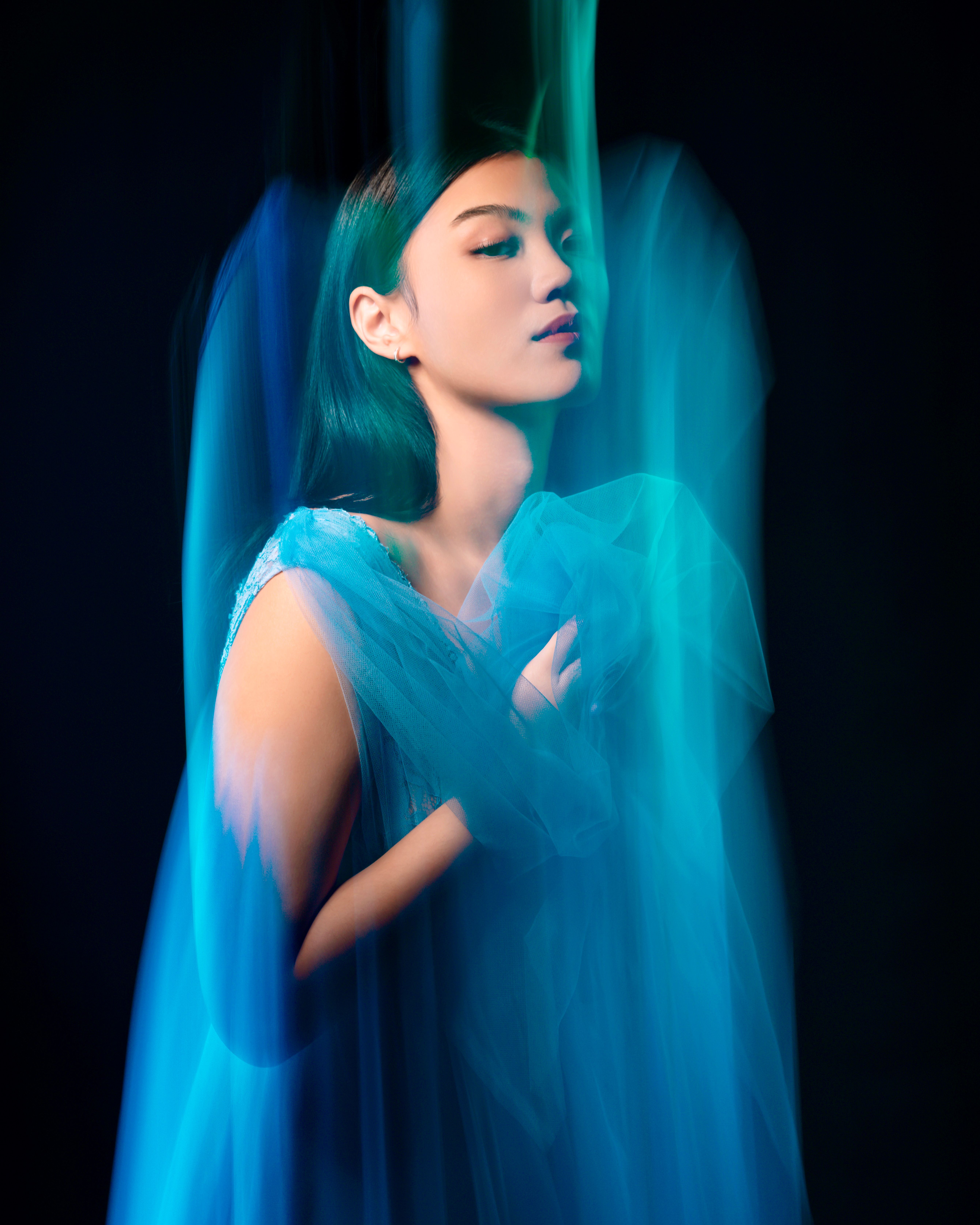 Creative portrait of a woman in blue fabric with dynamic movement and elegant pose.