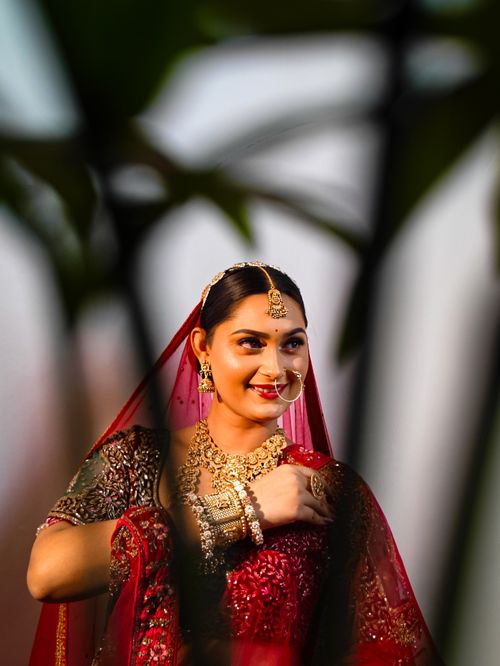 Free A beautiful bride adorned in traditional red attire with intricate jewelry, exuding elegance and charm. Stock Photo