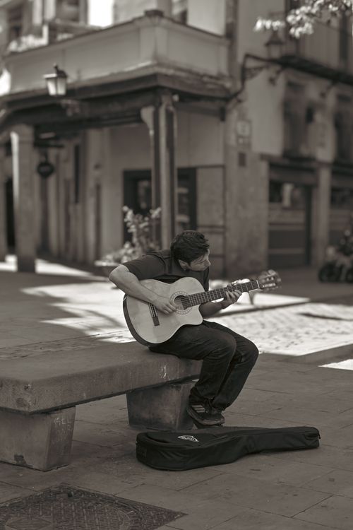 Free A street musician performs on guitar in an urban setting, creating a classic atmosphere. Stock Photo