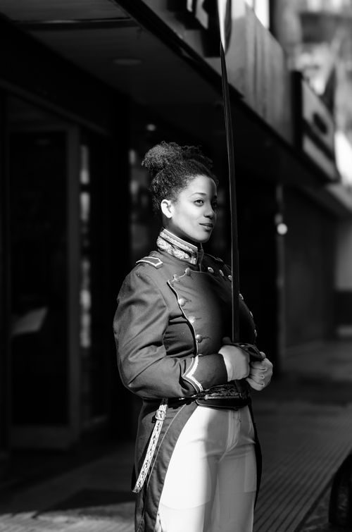 Free Black and white portrait of a woman in a historical military uniform holding a sword. Stock Photo