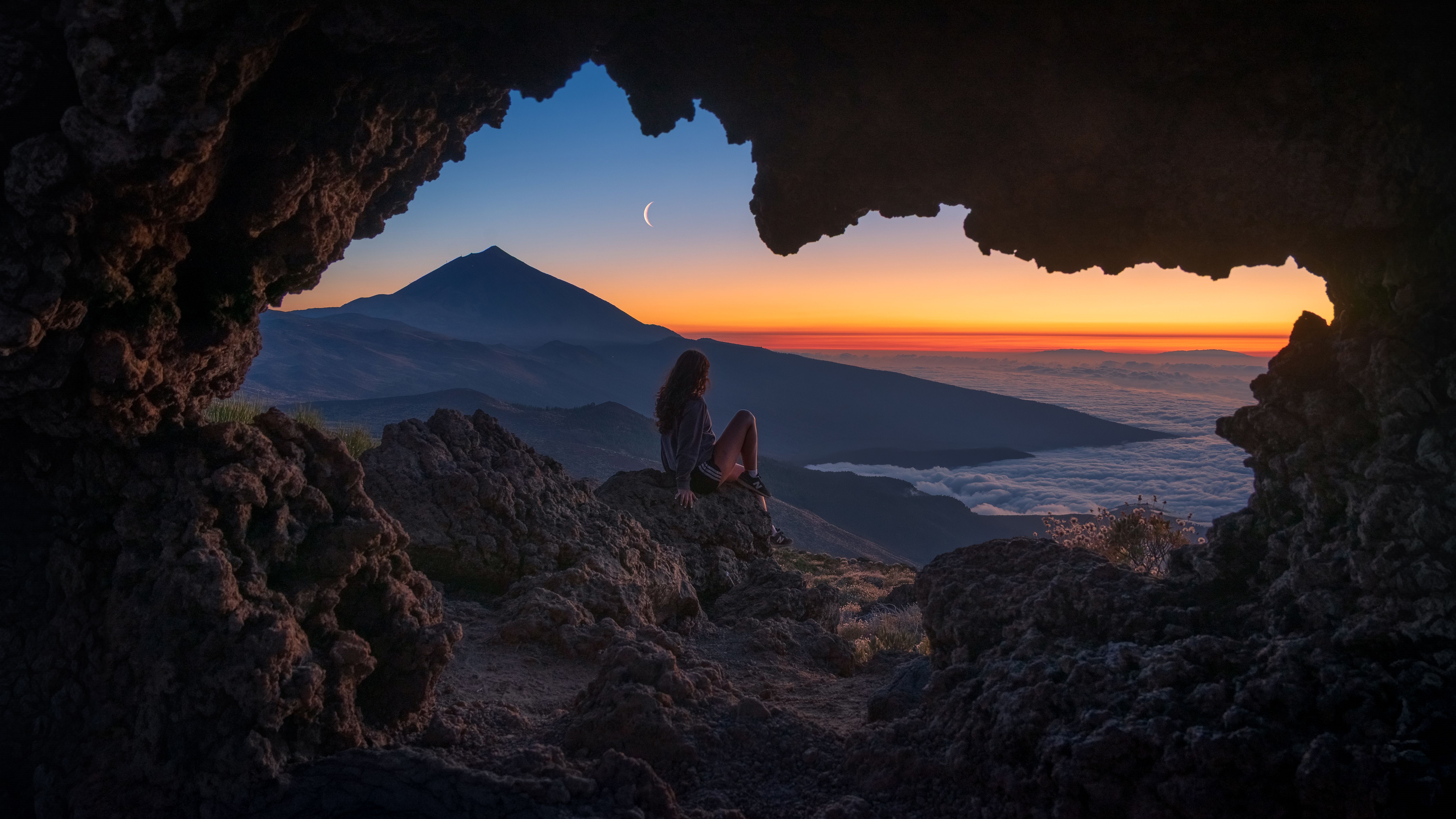 Sitting in cave watching twilight mountain scenery above sea of clouds