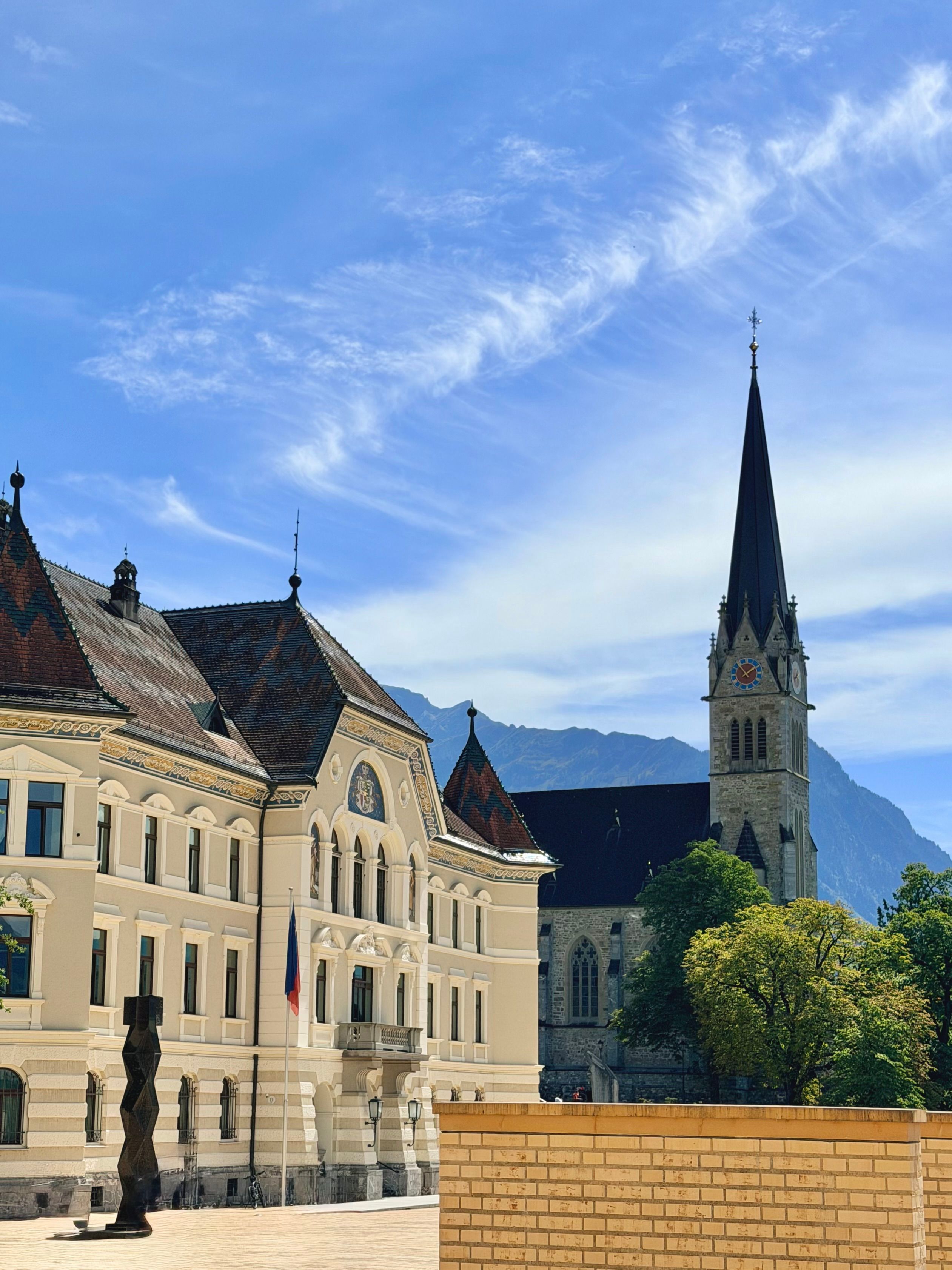 Sunlit view of Vaduz with the striking Cathedral of St. Florin set against the Alps.