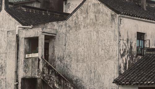 Free A close-up of an old and weathered building with peeling paint and moss growth on its walls. Stock Photo