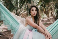 一位迷人的女子头戴王冠，在热带树叶间的吊床上放松身心