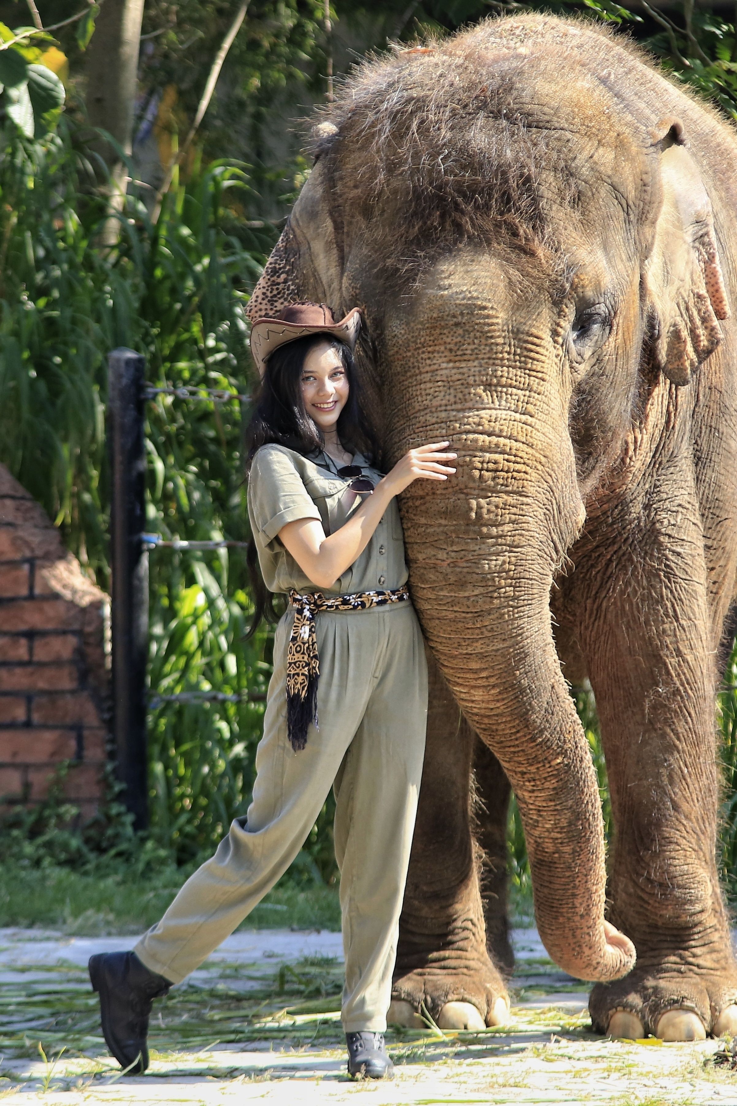 Smiling woman poses with Asian elephant in Surakarta, Indonesia zoo.