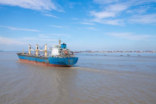 Free Cargo ship sailing in the Karnaphuli River under blue skies in Chattogram, Bangladesh. Stock Photo