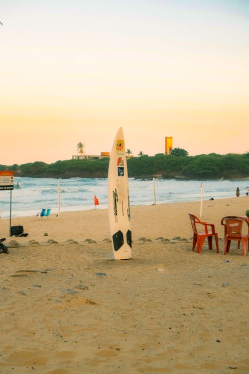 Free A lone surfboard stands on the sandy beach in Rio Grande do Norte, Brazil, during a beautiful sunset. Stock Photo