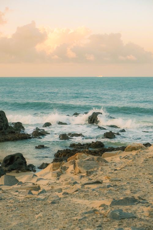 Free Scenic view of the Brazilian coastline with rocky shores and waves under a pastel sky. Stock Photo