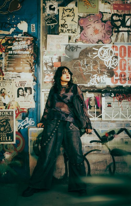 Free Fashionable person posing against a graffiti wall showcasing urban style and creativity. Stock Photo