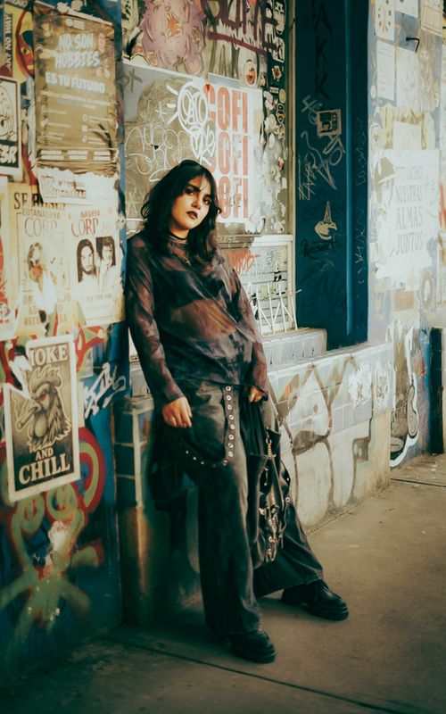 Free Stylish portrait of a woman in urban setting, leaning against graffiti-covered wall. Stock Photo