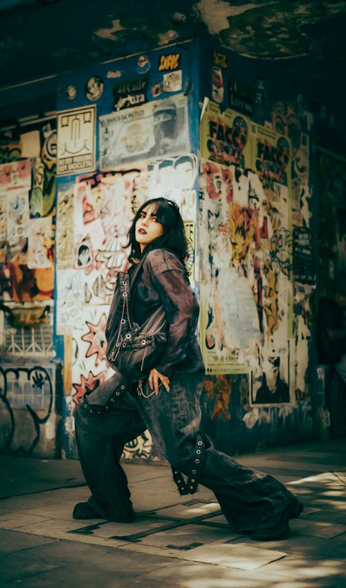 Free A stylish adult posing in an urban alleyway adorned with colorful graffiti and posters. Stock Photo