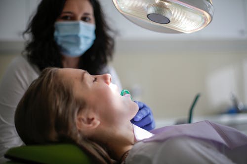 Dental assistant holding saliva ejector in mouth of patient