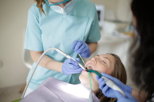 Crop dentists curing teeth of patient