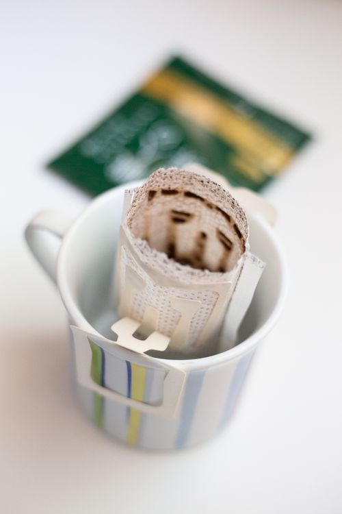 Free Closeup of a pour-over coffee bag in a striped mug on a bright surface. Stock Photo