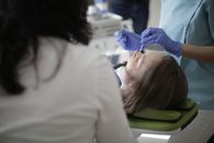 Faceless female dentist using drill and mouth mirror while curing teeth of patient