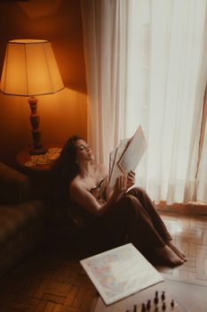 A woman relaxes by a window, enjoying a record in a warm, cozy setting.