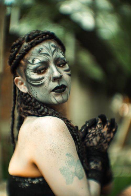 Free Creative portrait of a person with dramatic Halloween makeup and costume in a garden setting. Stock Photo