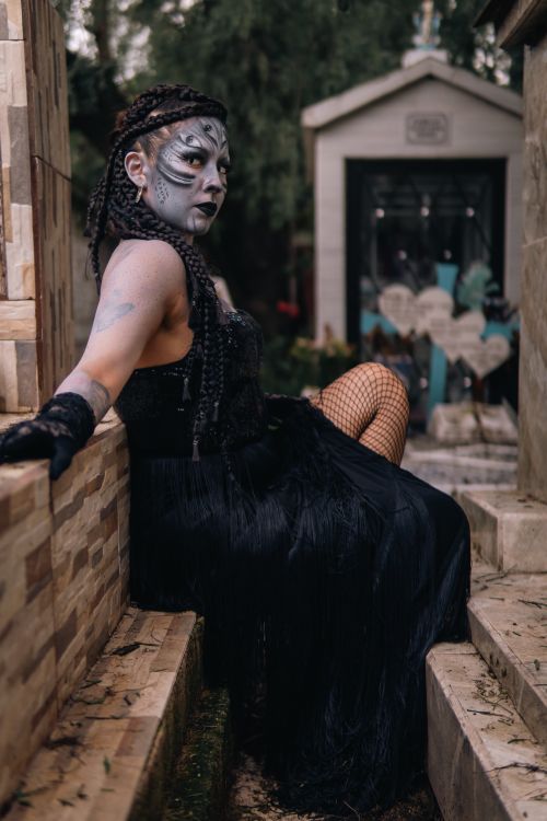 Free Portrait of a woman in artistic Halloween makeup sitting outdoors. Stock Photo