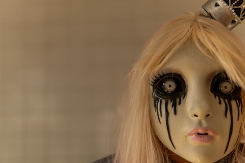 Free A haunting doll-like mask with black dripping eye makeup, perfect for Halloween themes. Stock Photo