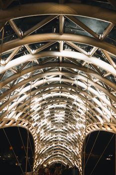 A captivating view of a futuristic, illuminated bridge with an arched roof design at night.