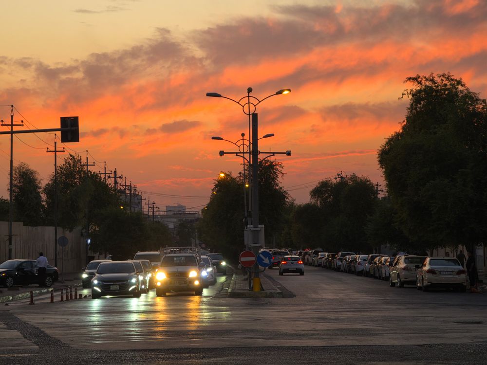 Urban street scene during sunset featuring cars and vibrant sky colors