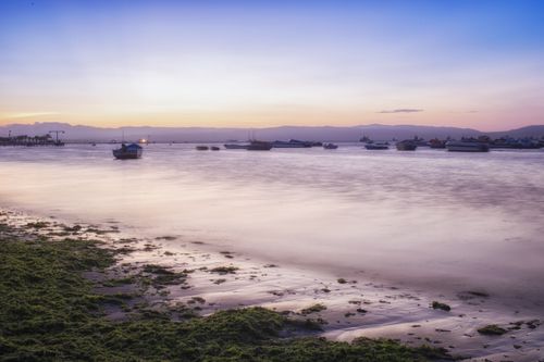 Free Tranquil sunset at Paracas Bay, Peru with boats on the calm sea. Stock Photo