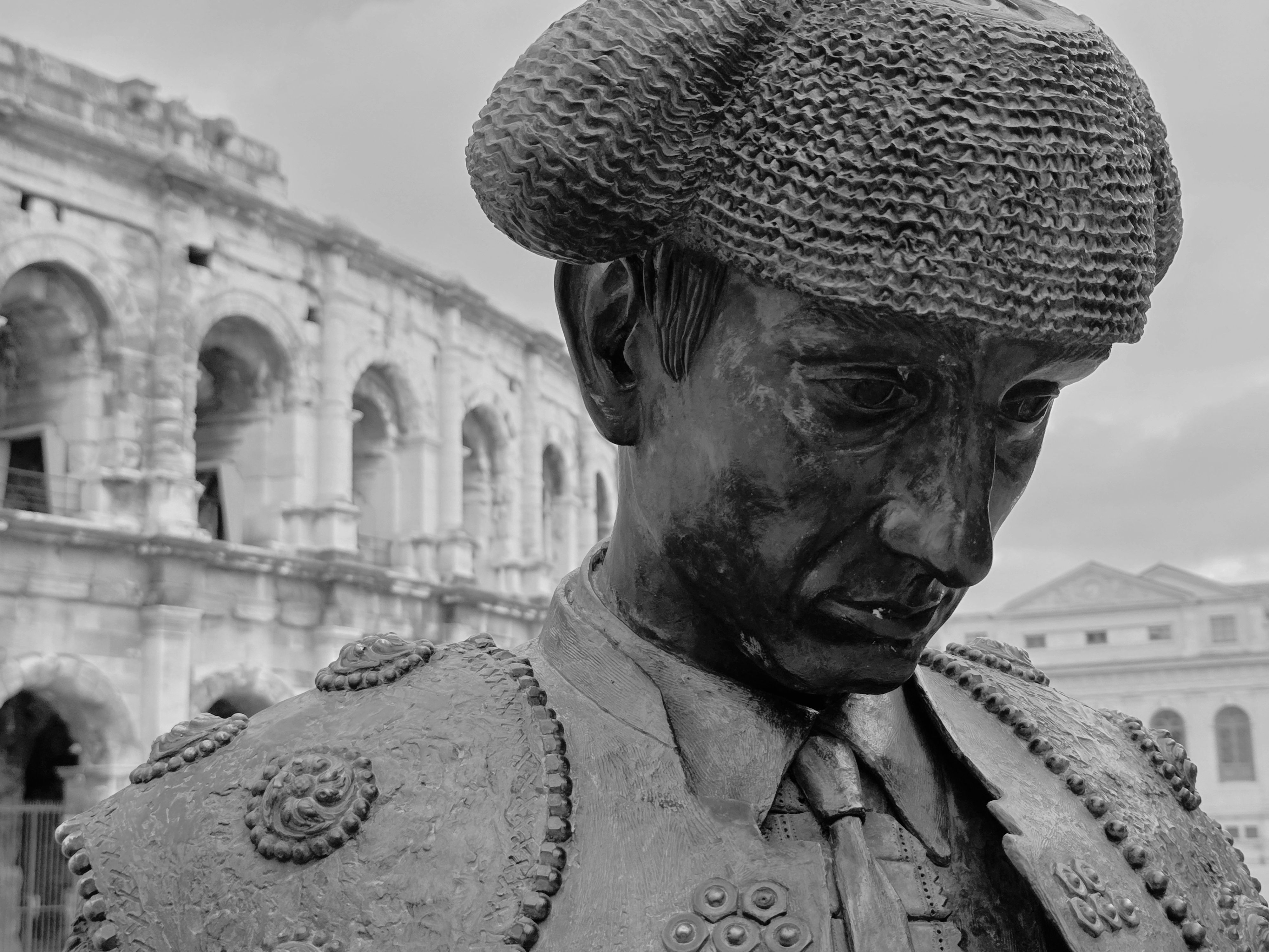 Black and white statue of a matador near the ancient Nîmes Amphitheater, France.