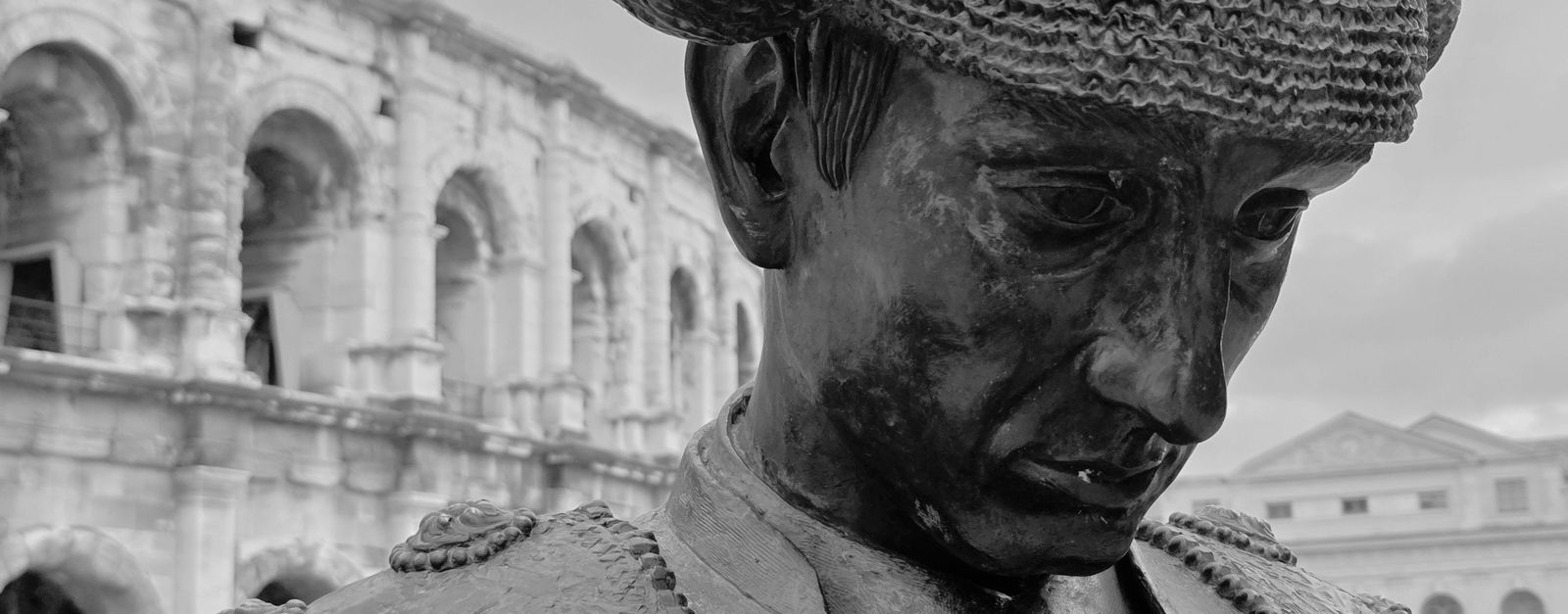 Black and white statue of a matador near the ancient Nîmes Amphitheater, France.