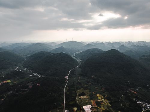 Free Dramatic aerial view of rolling mountains and valleys under a cloudy sky at dusk. Stock Photo