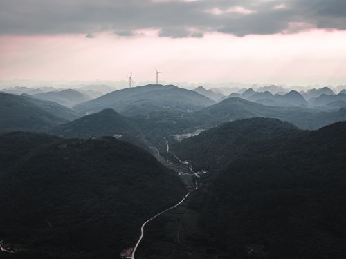 Free Dramatic aerial view of mountains with wind turbines at twilight, creating a serene and moody atmosphere. Stock Photo