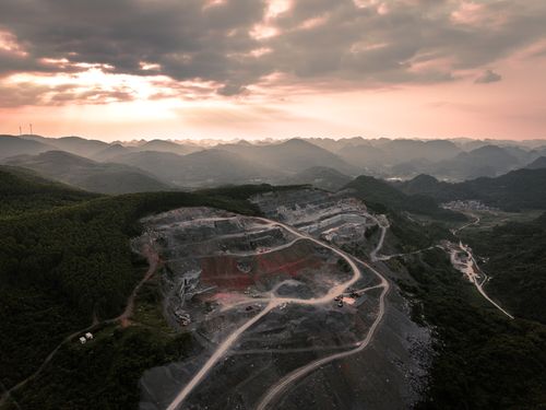 Free Dramatic aerial view of a quarry amidst rolling hills during sunset. Stock Photo
