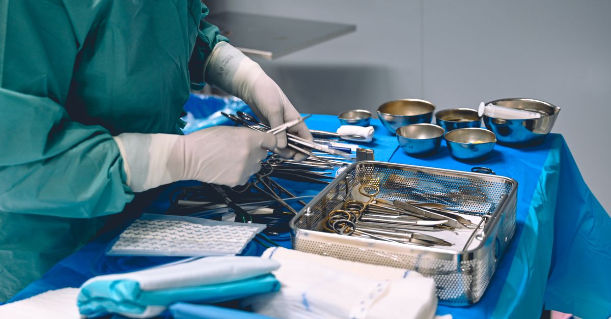 A surgeon organizing surgical tools on a sterile table in an operating room.