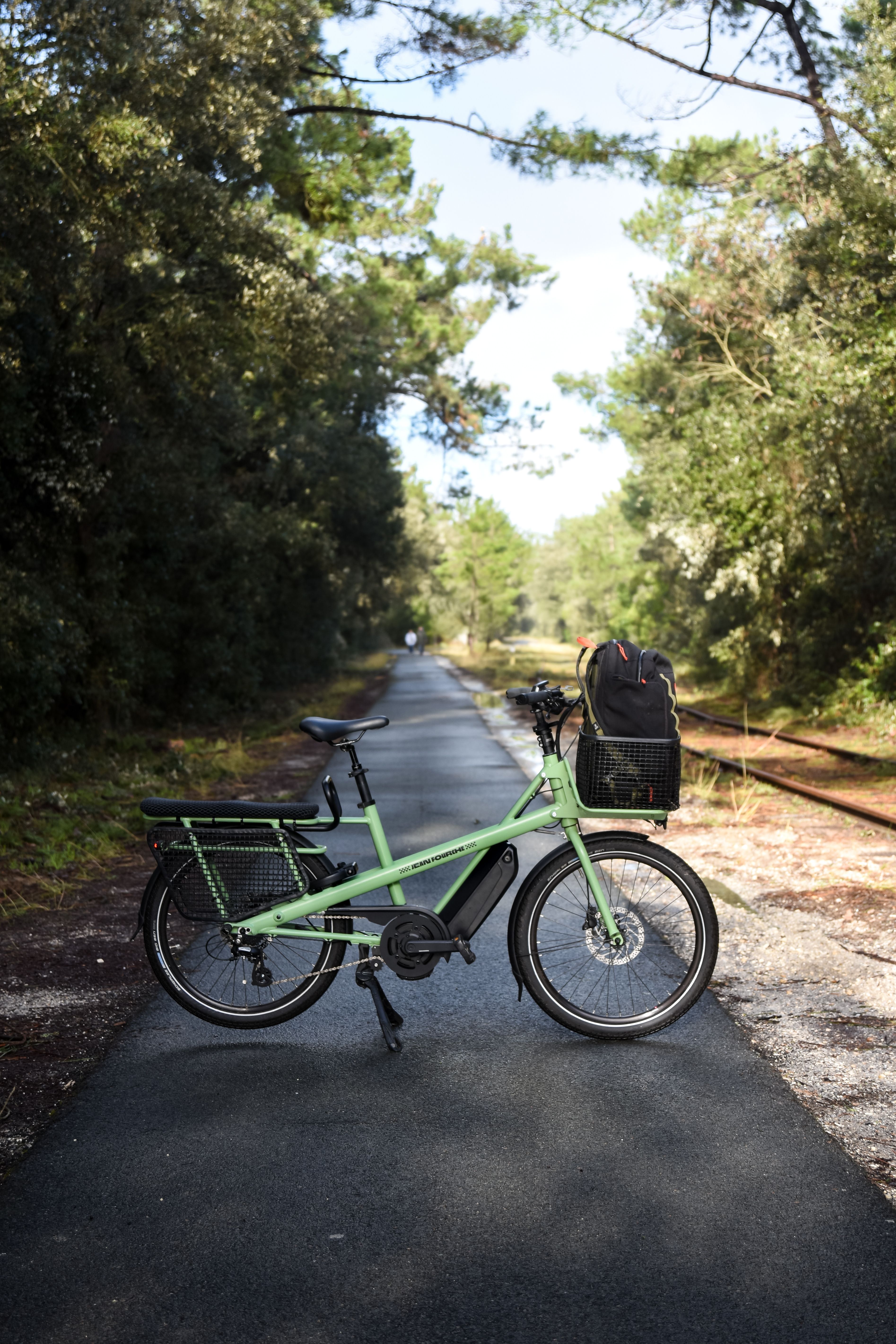 Green e-bike parked on a sunny forest path, ideal for nature travel.