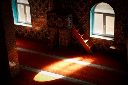 Free A sunbeam illuminates the richly patterned interior of a mosque, highlighting intricate details. Stock Photo