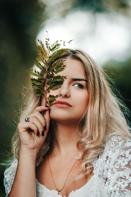A captivating portrait of a woman holding a fern leaf, creating a blend of elegance and nature.
