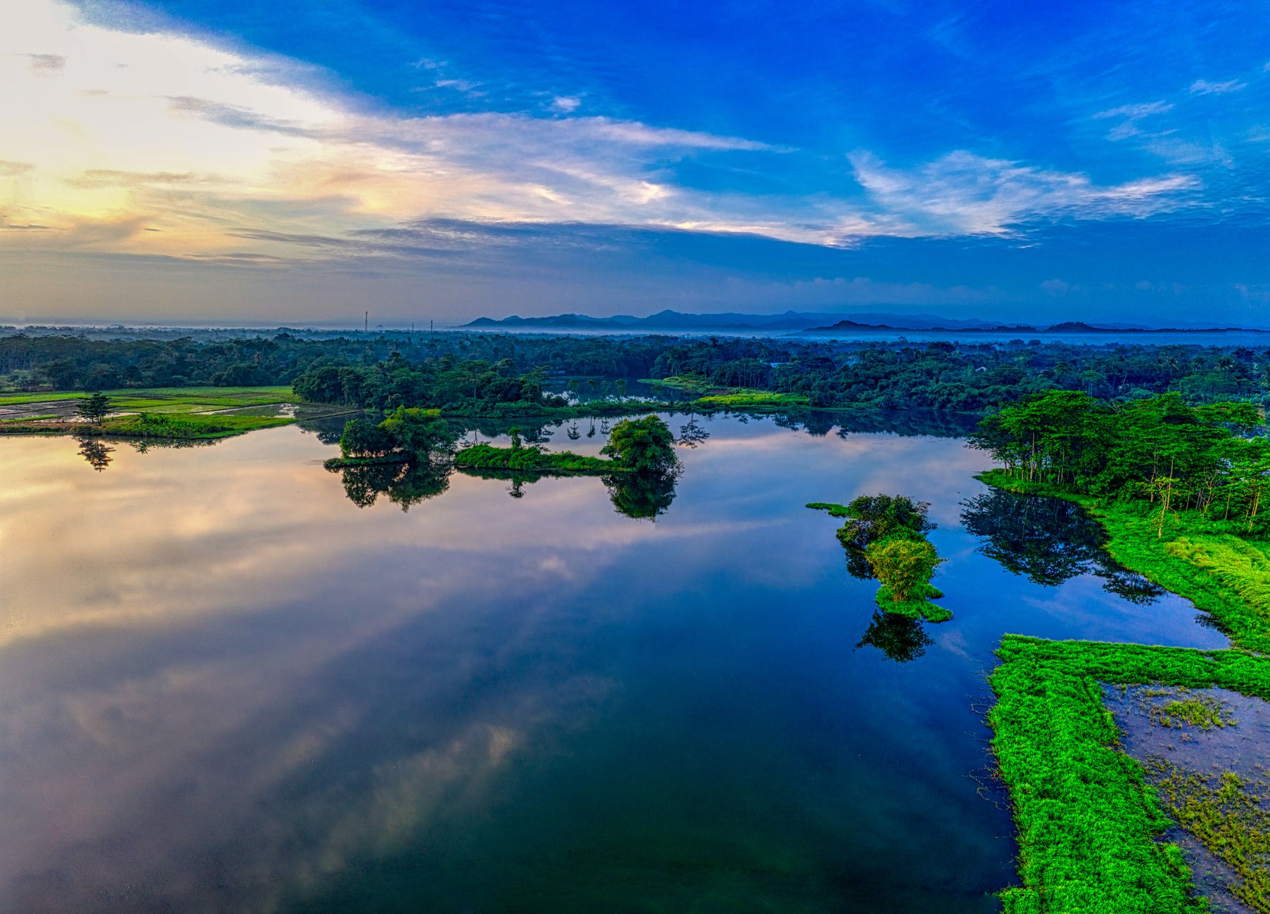 Aerial shot of a tranquil lake with lush greenery and clear reflections in Banten, Indonesia.