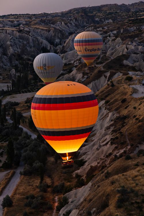 Free Colorful hot air balloons soar over Cappadocia's unique landscape at sunrise. Stock Photo