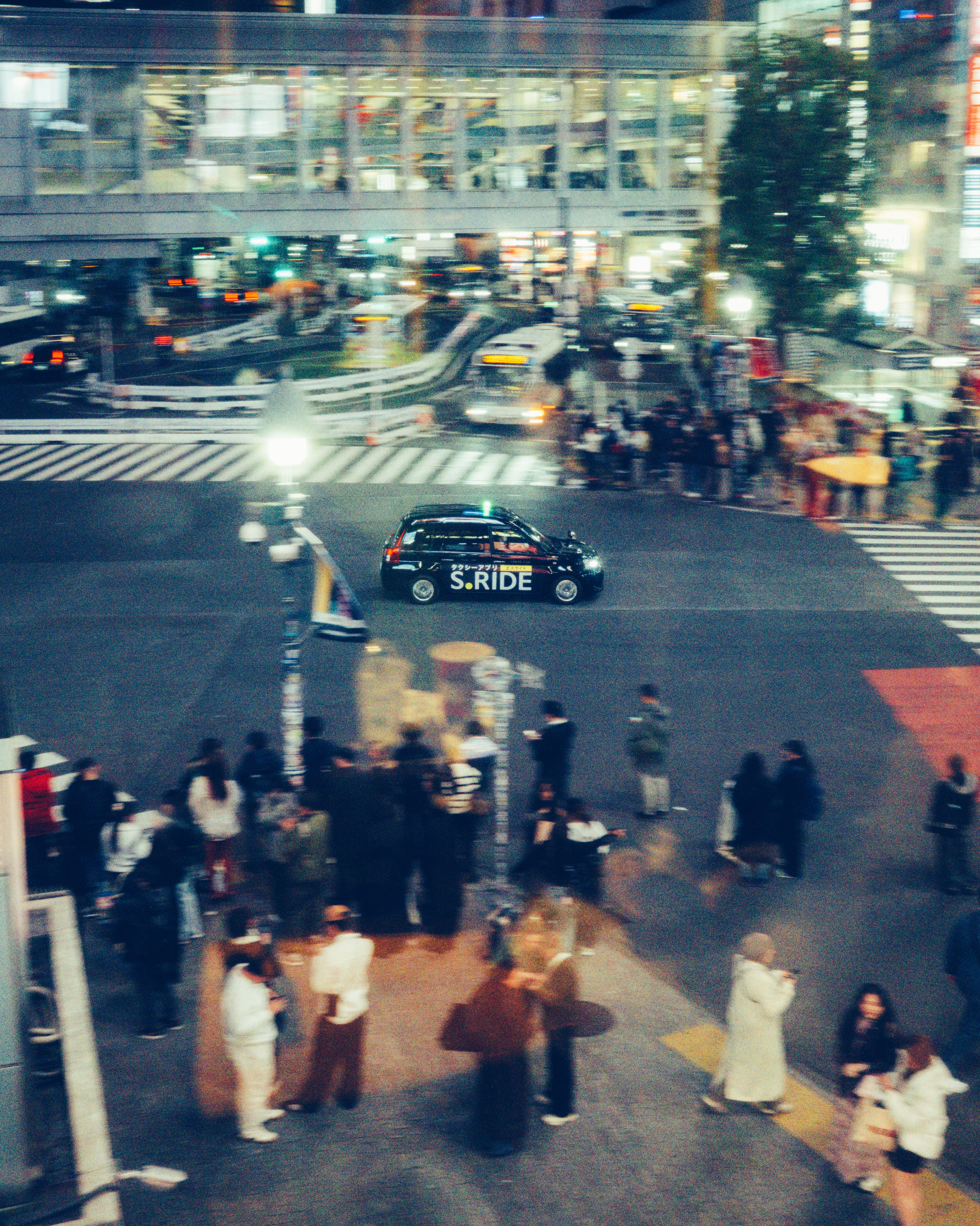 Fotomural Una vibrante escena nocturna de una concurrida intersección en Tokio, con multitud de gente y taxis.
