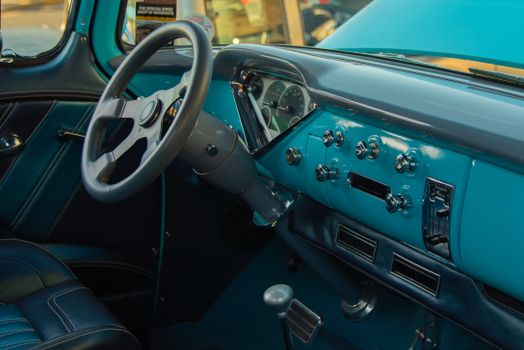 Close-up of a vintage car dashboard featuring aqua blue interior with classic design elements.
