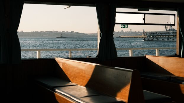 Peaceful seaside view through a ferry window showcasing the distant coastline and lighthouse.
