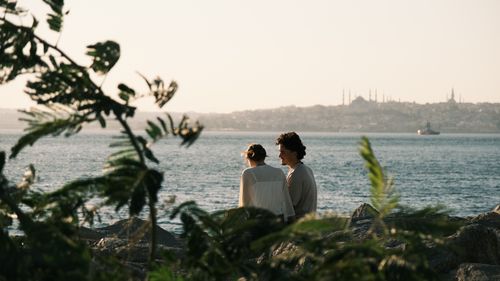 Free A couple enjoys a peaceful moment by the Bosphorus, overlooking the iconic Istanbul skyline at sunset. Stock Photo