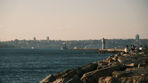 Free Relaxing sunset view of a city skyline and lighthouse by the sea shore. Stock Photo