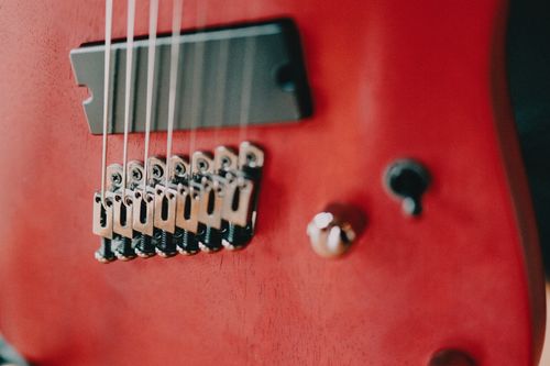 Free Detailed view of electric guitar strings and bridge on a red body, emphasizing musical craftsmanship. Stock Photo
