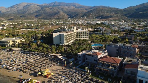 Free Stunning aerial view of beachfront hotels and lush mountains in Malia, Greece. Stock Photo