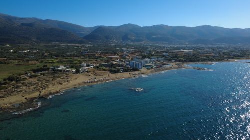 Free Stunning aerial shot of Malia beach with majestic mountains and clear blue waters in Greece. Stock Photo