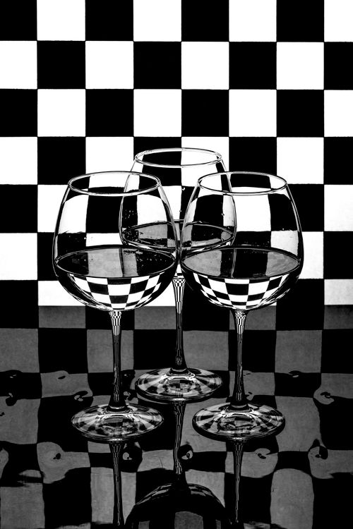 Free Black and white photo showcasing three wine glasses reflecting a checkerboard pattern. Stock Photo