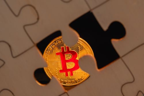 Free A bitcoin coin partially hidden under a puzzle piece on a wooden surface, symbolizing digital investment complexity. Stock Photo