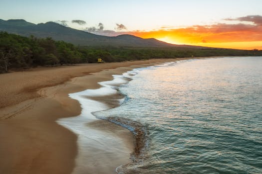 Serene sunset at Makena Beach, Maui, with ocean waves lapping the shore.